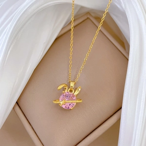 Close-up of pink rabbit pendant necklace with gold planet ring in jewelry box