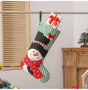Close-up of green striped Christmas stocking with snowman motif and gift box decor