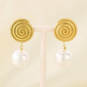 Detail of elegant gold spiral metal earrings with large white pearl drop on pink stand