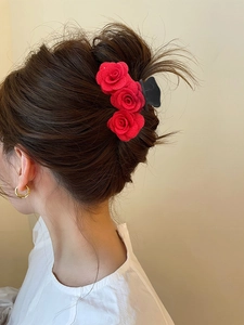 Detail view of a model wearing a triple red flocked rose hair claw clip for a refined updo
