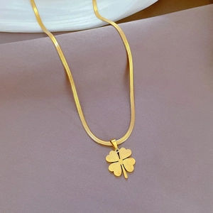 Detailed macro view of a gold four-leaf clover pendant on a sleek snake chain necklace