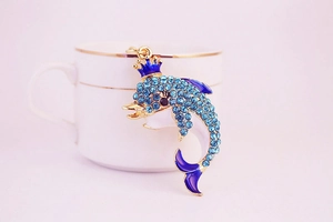 Detail of a gold crown dolphin keychain encrusted with blue rhinestones and blue enamel