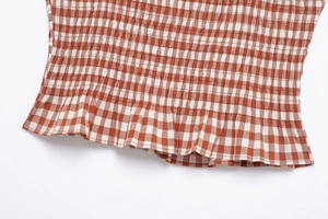 Close-up of red and white checkered smocked fabric with elastic texture and ruffled hem detail