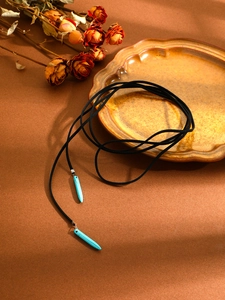 Artistic detail of bohemian turquoise stone pendant necklace on a ceramic plate