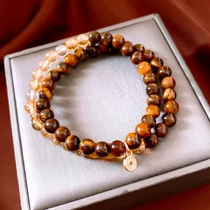 Bracciale a doppio strato in perle di occhio di tigre e vetro con ciondolo dorato