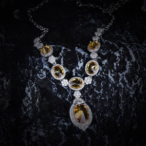 Detailed close-up of a silver necklace featuring large oval yellow gemstones and small crystals