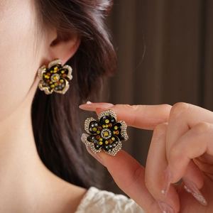 Close-up of vintage flower earrings with yellow and orange rhinestones on a black base