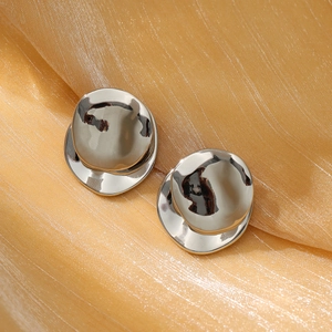 Macro view of irregular geometric silver stud earrings on champagne silk fabric