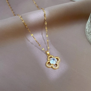 Detailed close-up of a golden four-leaf clover pendant with zircon inlay on silk background