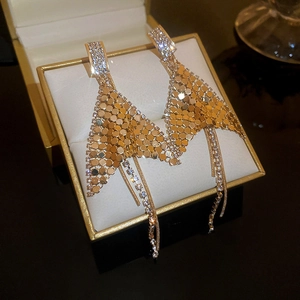 Macro view of gold fishtail sequin tassel earrings with rhinestones in a gift box