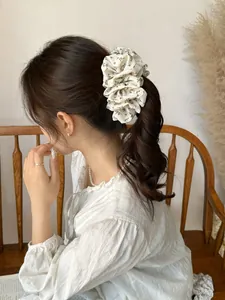 Detail of cream floral scrunchie on a ponytail featuring elegant chiffon pleats