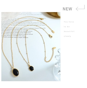 Detail of vintage gold-plated necklaces with oval black cat-eye pendants on magazine