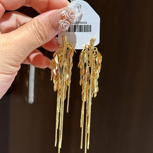 Dettaglio di orecchini a foglia dorata con lunghe nappe metalliche e etichetta prodotto