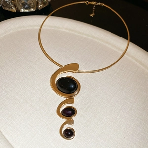 Detail of vintage style gold collar necklace with oval black resin stone on a tray