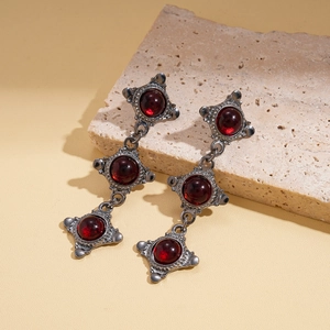 Detail of retro silver-tone drop earrings with three red resin circular stones on stone