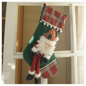Detail of a green plush Christmas stocking with a 3D Santa Claus and tartan accents