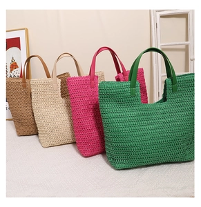 Detail view of four large woven straw tote bags in brown beige rose and green colors