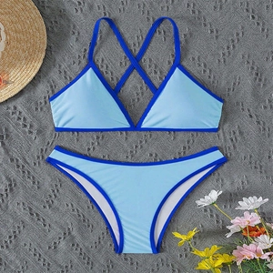 Flat lay of light blue bikini set with royal blue trim and summer vacation accessories
