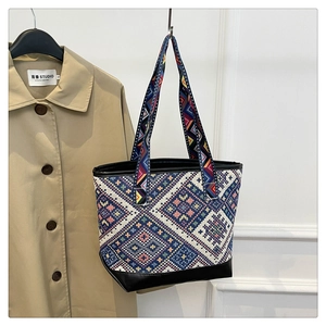 Detail of ethnic geometric woven pattern and black leather base on a large tote bag