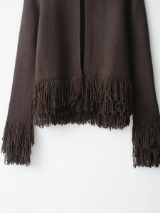 Détail d'un cardigan en maille marron foncé avec des franges sur les poignets et l'ourlet
