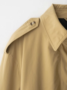 Vue macro détaillée du trench-coat kaki montrant les épaulettes, le col et les boutons