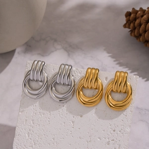 Detail of minimalist geometric layered earrings in gold and silver on white stone