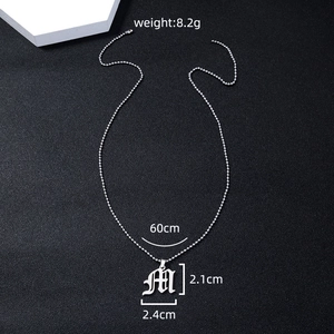 Detailed view of silver cursive letter M pendant with 60cm chain on dark background