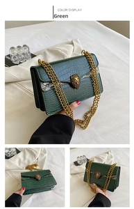 Detail of green faux crocodile skin texture and gold lion head clasp on the shoulder bag