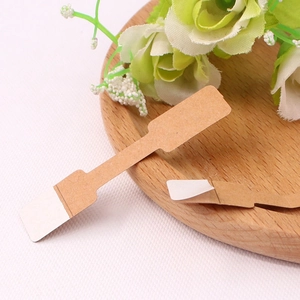 Macro detail of self-adhesive kraft paper jewelry labels shown on a wooden plate