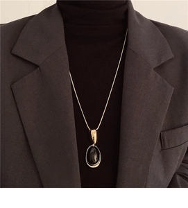 Detailed view of oval resin pendant necklace styled on professional business attire