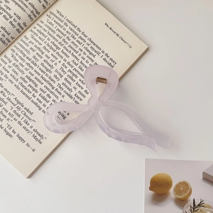 Macro detail of a translucent lavender bow claw clip on a book with matte finish