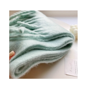 Close-up of thick mint green mohair scarf featuring soft texture and fringe details