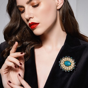 Vintage sunburst brooch with turquoise stone and blue rhinestones on black suit