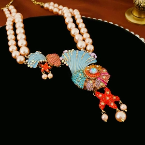 Detail of double-layer pearl necklace with starfish and seashell charms in crystal pavé