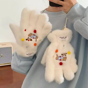 Detail of plush white puppy gloves featuring colorful pom-poms and cute dog embroidery