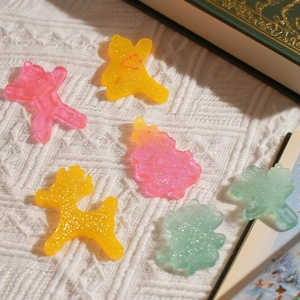 Glitter resin Christmas charms with bear and deer shapes on a white knit background