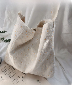 Detail of daisy embroidery on cream canvas tote bag with a single shoulder strap