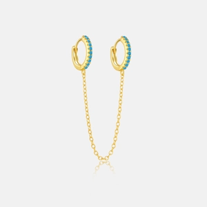 Close-up of golden chain earrings with blue stones and polished double hoops
