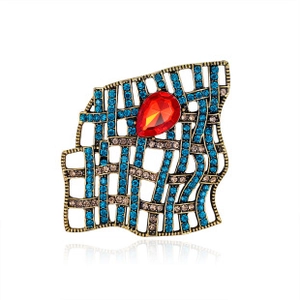Close-up of vintage gold alloy brooch with blue rhinestones and red teardrop gemstone