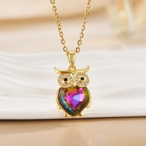 Macro detail of golden owl pendant featuring a rainbow crystal heart and crystal eyes