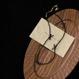 Macro shot of black spinel bead necklace with delicate bow accents on a wooden tray