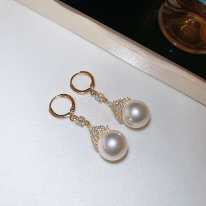 Détail de boucles d'oreilles perles rondes dorées avec des accents de zircon brillant