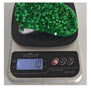 Detail shot of a green sequin Christmas stocking ornament weighing 10g on a scale