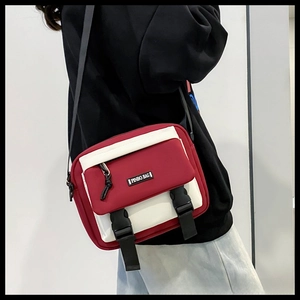 Detailed view of the red and white patchwork messenger bag with plastic buckle closures