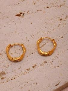 Détail de boucles d'oreilles torsadées dorées sur pierre avec placage PVD or 18 carats