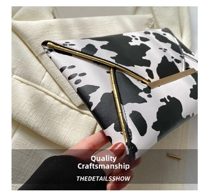 Close-up of cow print envelope clutch bag with elegant gold metal trim detail