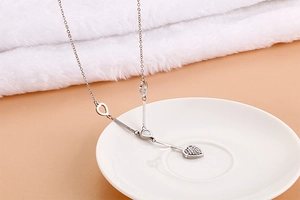 Detailed view of silver heart and bar pendant necklace on elegant white ceramic dish