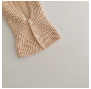 Detailed close-up of apricot ribbed knit fabric texture and white round buttons