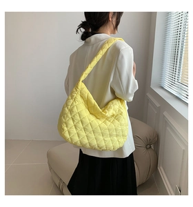 Detail of yellow quilted tote bag with wide strap worn by model in a modern setting