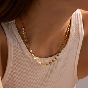 Close-up of bohemian gold flower necklace with blue gems on female model neck